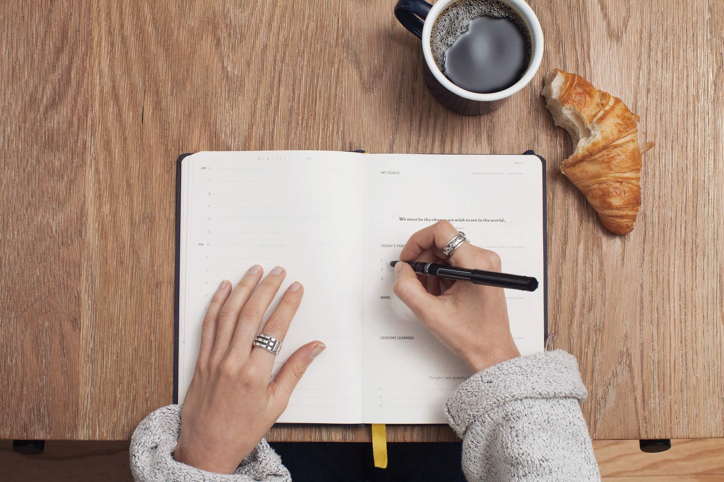 Schreiben im Tagebuch mit Kaffee und Gebäck auf dem Tisch